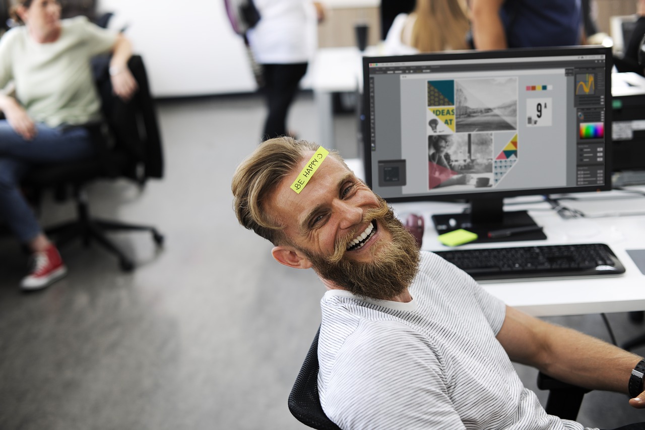 En la imagen aparece un hombre rubio de barba feliz trabajando en su oficina. Representa el artículo cuyo nombre es ¿como buscar trabajo con éxito?
